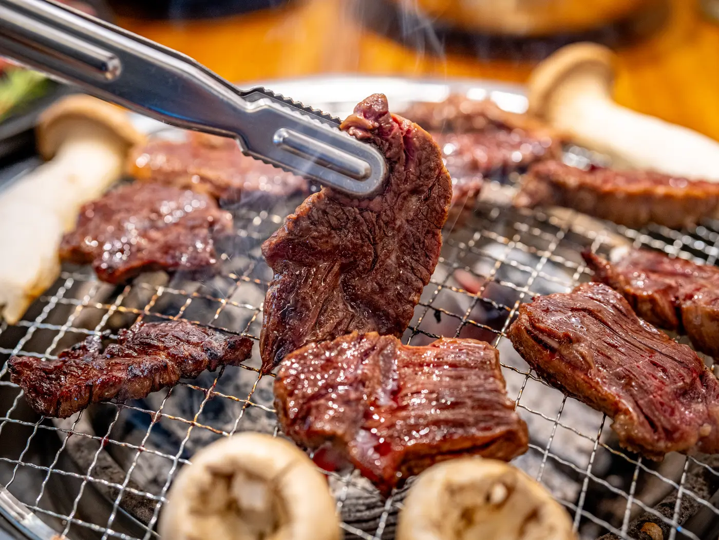 집게로 집어 올린 구운 소고기 한 점 — 근처 고깃집(焼肉 近く)을 찾는 이유